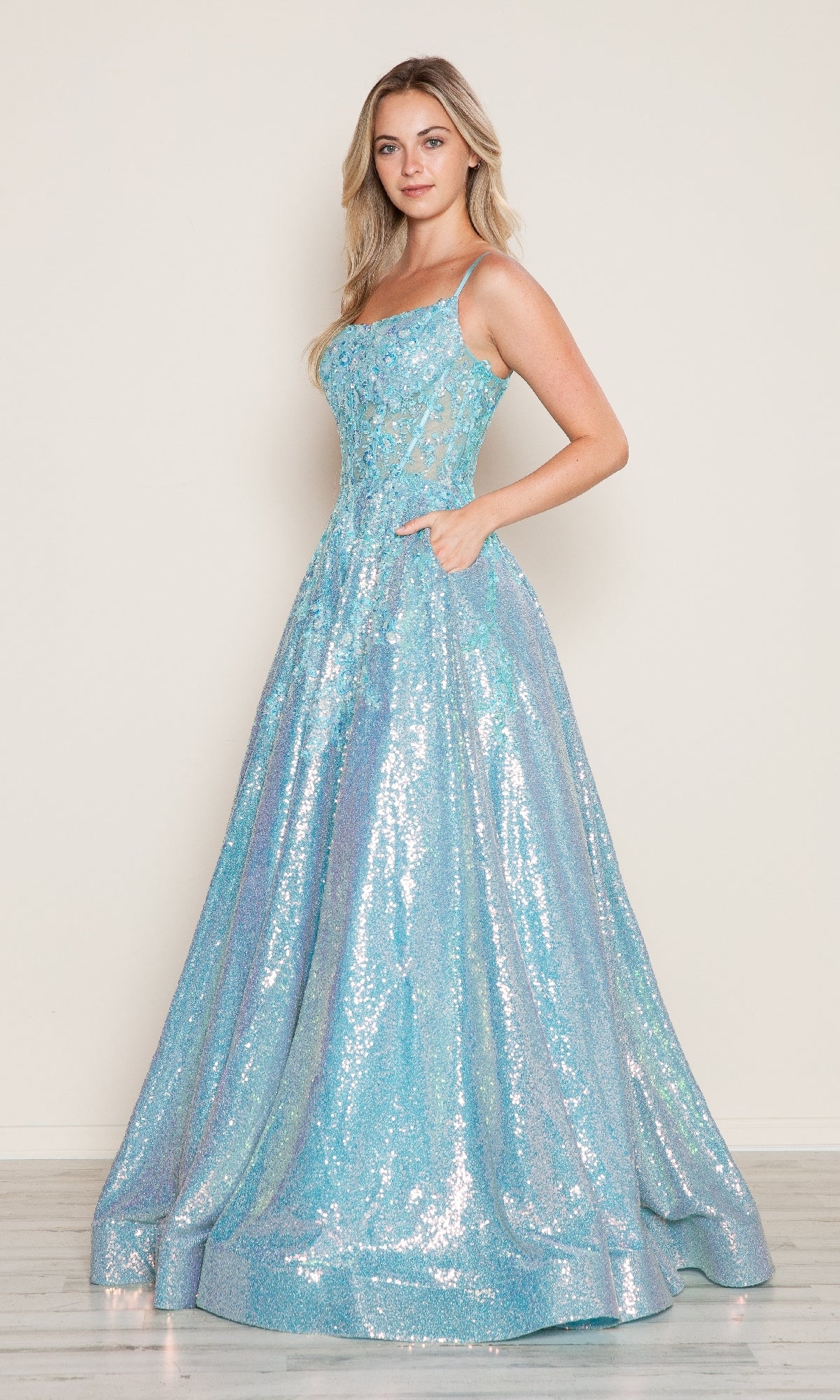 A woman stands against a plain background wearing the Poly USA 9554 Side-Pockets Long Sequin Prom Dress—a sleeveless, floor-length light blue gown featuring a fitted bodice and flared skirt.
